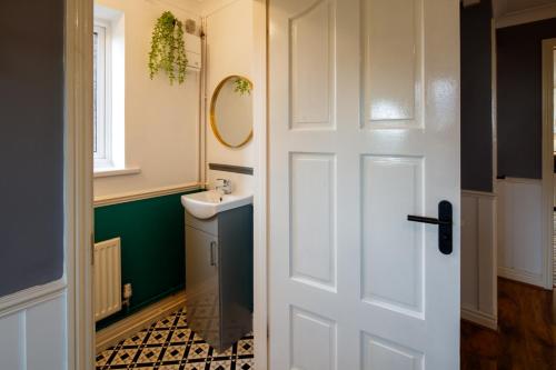 La salle de bains est pourvue d'une porte blanche et d'un lavabo. dans l'établissement Wellsway House by Cliftonvalley Apartments, à Bristol