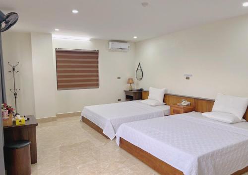 a hotel room with two beds and a window at Thu Ha Hotel in Uông Bí