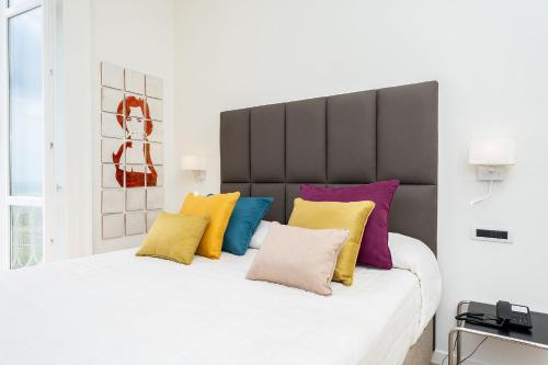 a bedroom with a large white bed with colorful pillows at Palazzo Ferraioli - Hotel & Wellness in Atrani