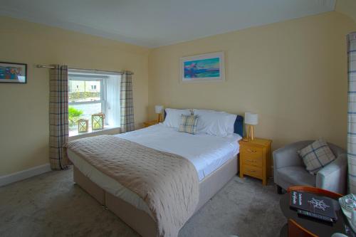 um quarto com uma cama, uma cadeira e uma janela em The Harbour Inn em Garlieston