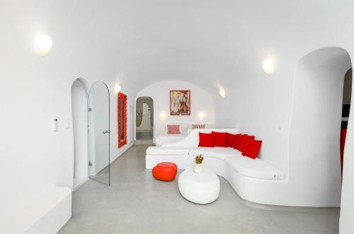 a white living room with a white couch and red pillows at Trieris Villa & Suites in Fira