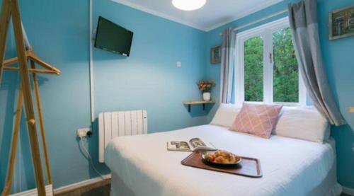 a blue bedroom with a bed with a tray of fruit on it at Rebels Retreat - 2-Bed Chalet nr St Ives & Hayle in St Ives