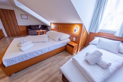 1 dormitorio con 2 camas y toallas blancas. en Szinbád Hotel, en Pécs