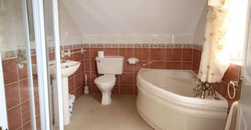 y baño con bañera, aseo y lavamanos. en Jackie's Cottage, en Claddaghduff