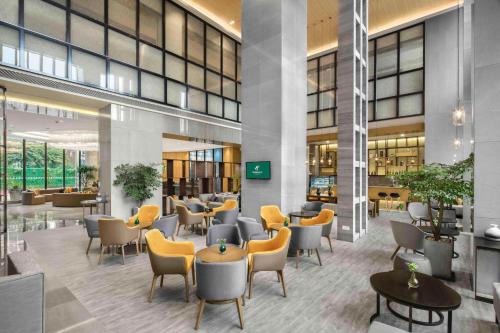 a lobby with chairs and tables in a building at Holiday Inn Chengdu Airport by IHG - Free Shuttle to Shuangliu International Airport in Chengdu