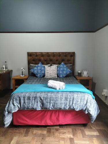a bedroom with a large bed with blue pillows at Fair Haven in Bloemfontein