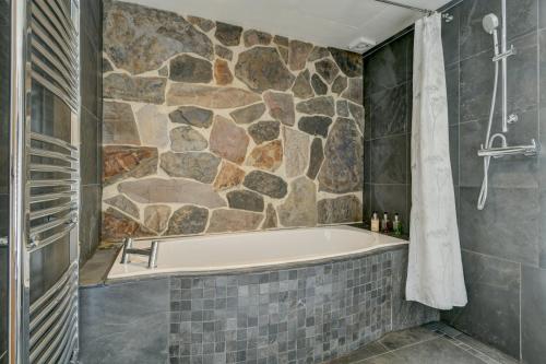 eine Badewanne im Bad mit einer Steinmauer in der Unterkunft Hartford Cottage West Anstey in East Anstey
