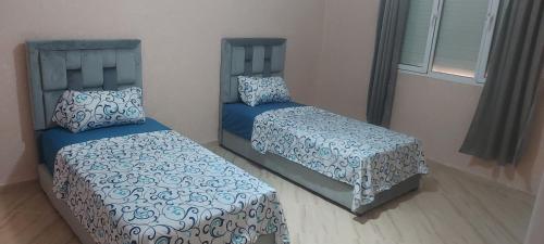 two beds in a bedroom with blue covers at Villa bien equiper a saidia pres de la plage in Saïdia
