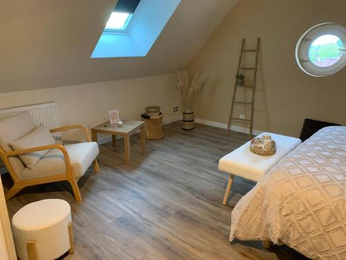 a bedroom with a bed and chairs and a skylight at Les 3 chambres de Christelle & Gilbert in Margon