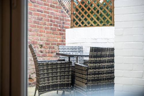 two chairs and a table in front of a brick wall at Whitley Haven, Luxury Seaside Apartment in Whitley Bay