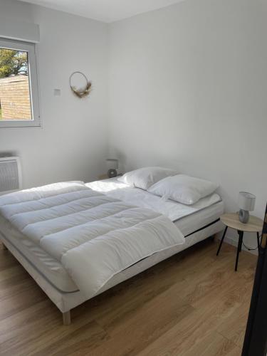 ein großes weißes Bett in einem Schlafzimmer mit Fenster in der Unterkunft Les Chalets du Mancel : Chalet Lulu - Bouleries Jump - 24h du Mans in Parence