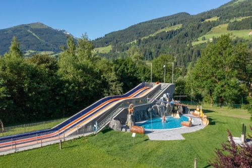 a slide in a park with a swimming pool at Aktiv- & Gesundheitsresort das GXUND in Bad Hofgastein