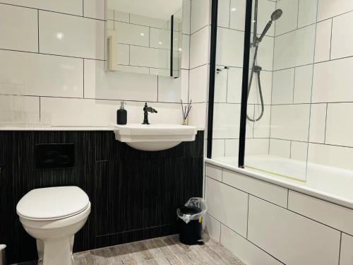 a bathroom with a toilet and a sink and a shower at Homely 2-Bed Apartment with stunning Views Wembley in London