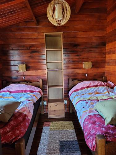 two beds in a room with wooden walls at Op e Mieden in Bartlehiem