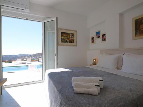a white bedroom with a bed with two towels on it at Chrysanthemo villas in Ano Mera