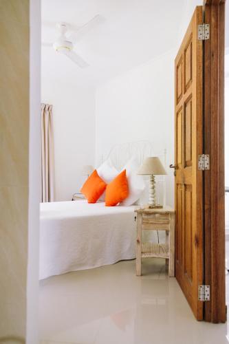 a bedroom with a bed with orange pillows and a table at SOUTH HILL VILLA in Mahe
