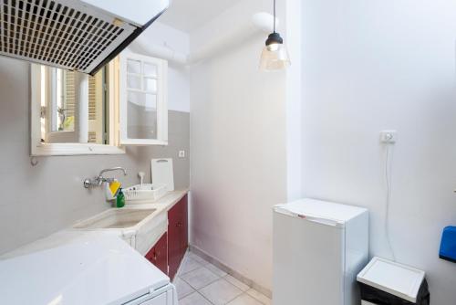 ein weißes Badezimmer mit einem Waschbecken und einem Kühlschrank in der Unterkunft Beautiful Neo-Classic apartment in Exarchia (1Bed) in Athen