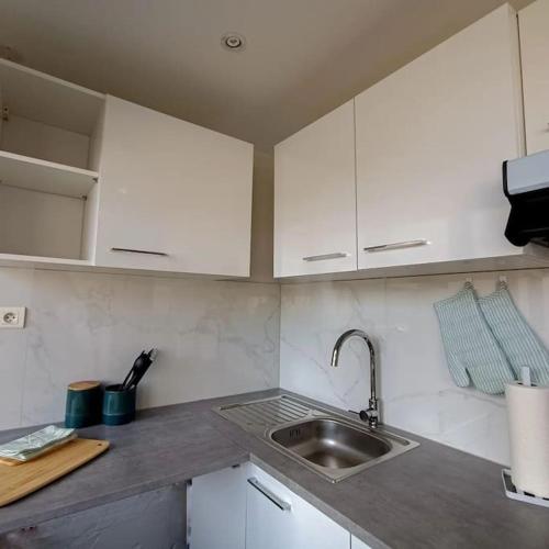 une cuisine avec des armoires blanches et un évier dans l'établissement Appartement proche du centre, à Mulhouse