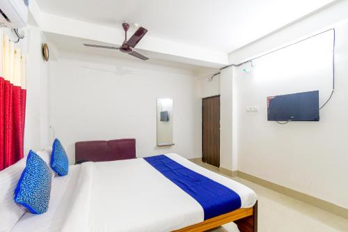 a bedroom with a bed with blue pillows and a tv at Eden Hotel in kolkata