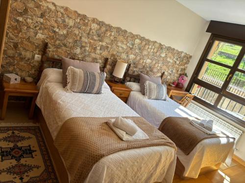 1 dormitorio con 2 camas y pared de piedra en Apartamento Mirador del Pantano2, en Vinuesa