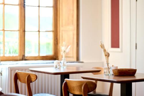 two tables and chairs in a room with a window at Hotel La Malle Poste in Rochefort