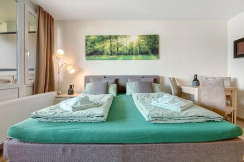 Schlafzimmer mit einem grünen Bett und einem Schreibtisch in der Unterkunft Ferienappartement Waldgenuss in Sankt Englmar