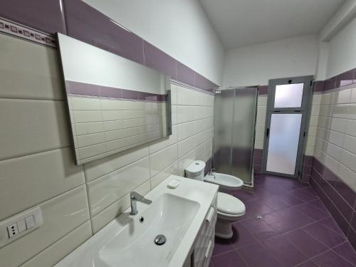 a bathroom with a sink and a toilet and a mirror at Appartamento Perla in Vlorë