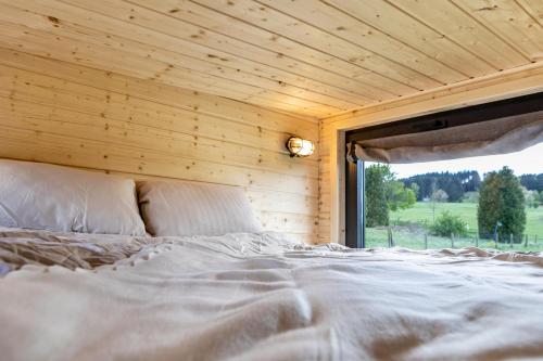 Ce lit se trouve dans une chambre en bois dotée d'une fenêtre. dans l'établissement Tiny House - Tinyinn No1, à Ulrichstein