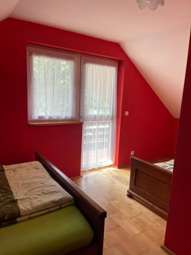 Schlafzimmer mit roten Wänden, einem Bett und einem Fenster in der Unterkunft Domek Letniskowy w Krzemiennej in Krzemienna
