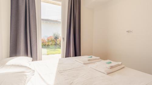 ein weißes Bett mit zwei Handtüchern darauf in der Unterkunft Rosa Dei Venti - Italian Homing in Padenghe sul Garda