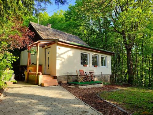 uma pequena casa branca com um alpendre e um pátio em Csendes pihenés az erdő mellett - Madárfüttyös Vendégház em Pilisszentlászló