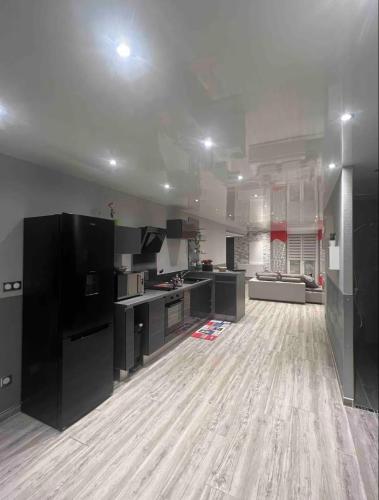 Il comprend une grande cuisine avec des placards noirs et du parquet. dans l'établissement Chez Amandine, à Osne-le-Val