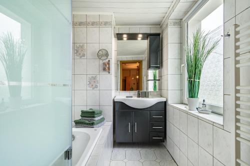 uma casa de banho com um lavatório, uma banheira e um espelho. em Ferienwohnung zum Specht 