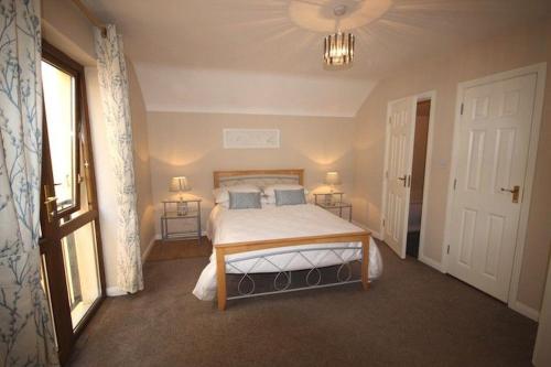 a bedroom with a bed and two lamps and a window at 2 Clifden Court in Clifden