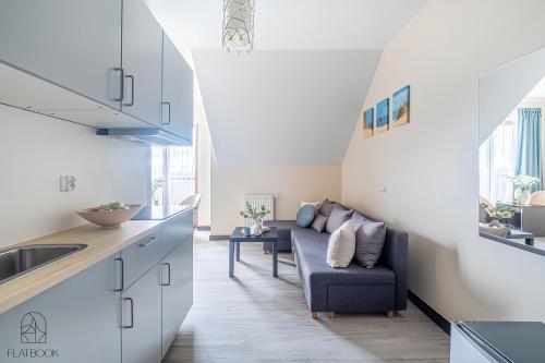 a kitchen and living room with a couch in a room at Flatbook - Sztutowo Lazurowy Dwór in Sztutowo