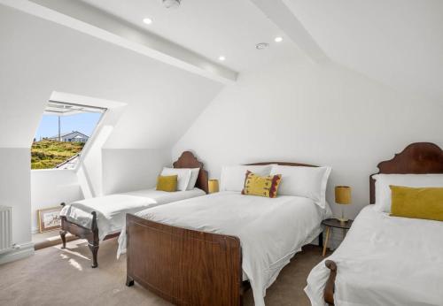 a attic bedroom with two beds and a window at Sweet Garden, Mannin - Ballyconneely in Ballyconneely
