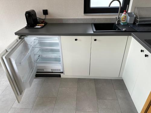 a kitchen with white cabinets and an open refrigerator at Domki Piwniczna in Piwniczna