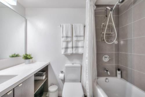 a white bathroom with a toilet and a bath tub at Premier INN in Toronto