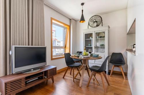 uma sala de estar com uma televisão e uma mesa com cadeiras em Breeze Apartment - Matosinhos em Matosinhos