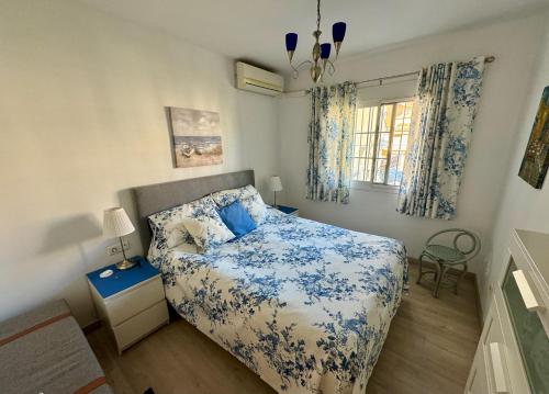 een slaapkamer met een blauw en wit bed en een raam bij Strandnära boende i Torrox Costa in Torrox Costa