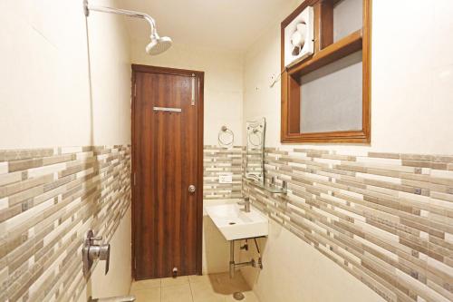 Hotel Red Stone Mahipalpur في نيودلهي: حمام مع حوض وباب خشبي
