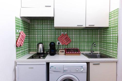 a green tiled kitchen with a washing machine and a sink at Davids Room Palazzo Tamborino in Lecce