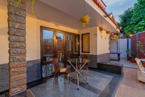 a patio of a house with a glass table and chairs at The Venue By Seasons Suites- in Dod Ballāpur