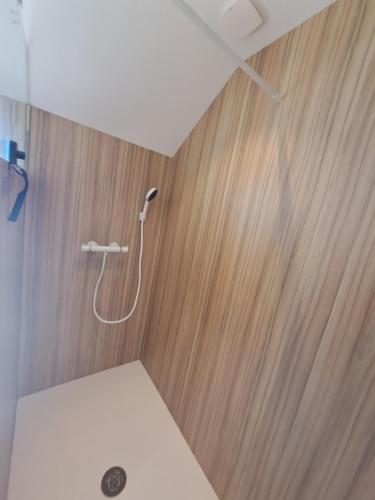 une douche dans une salle de bain avec un mur en bois dans l'établissement Les Goelettes à 250 m de la plage, à Barneville-Carteret