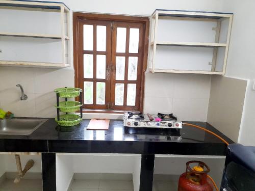 a kitchen with a black counter top and a window at Olive Garden Apartment in Candolim