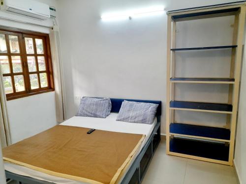 a small room with a bed and a book shelf at Olive Garden Apartment in Candolim