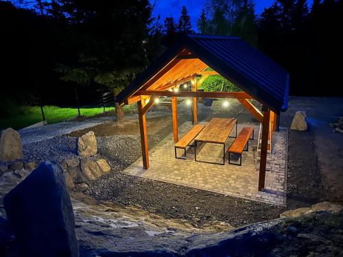 a gazebo with a picnic table and benches at Domki Piwniczna in Piwniczna