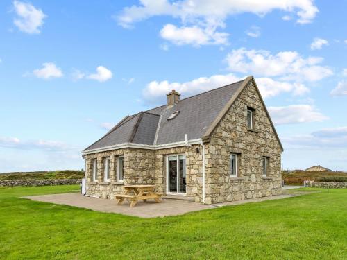 a stone house with a picnic table in a field at Lake House Mannin, Ballyconneely in Ballyconneely