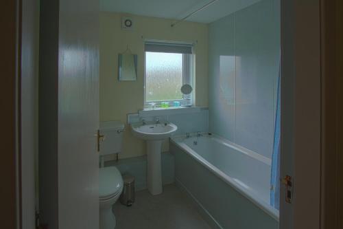 a bathroom with a sink and a toilet and a bath tub at Harbour Inn Appartments in Garlieston