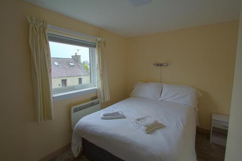 a small bedroom with a bed with a window at Harbour Inn Appartments in Garlieston